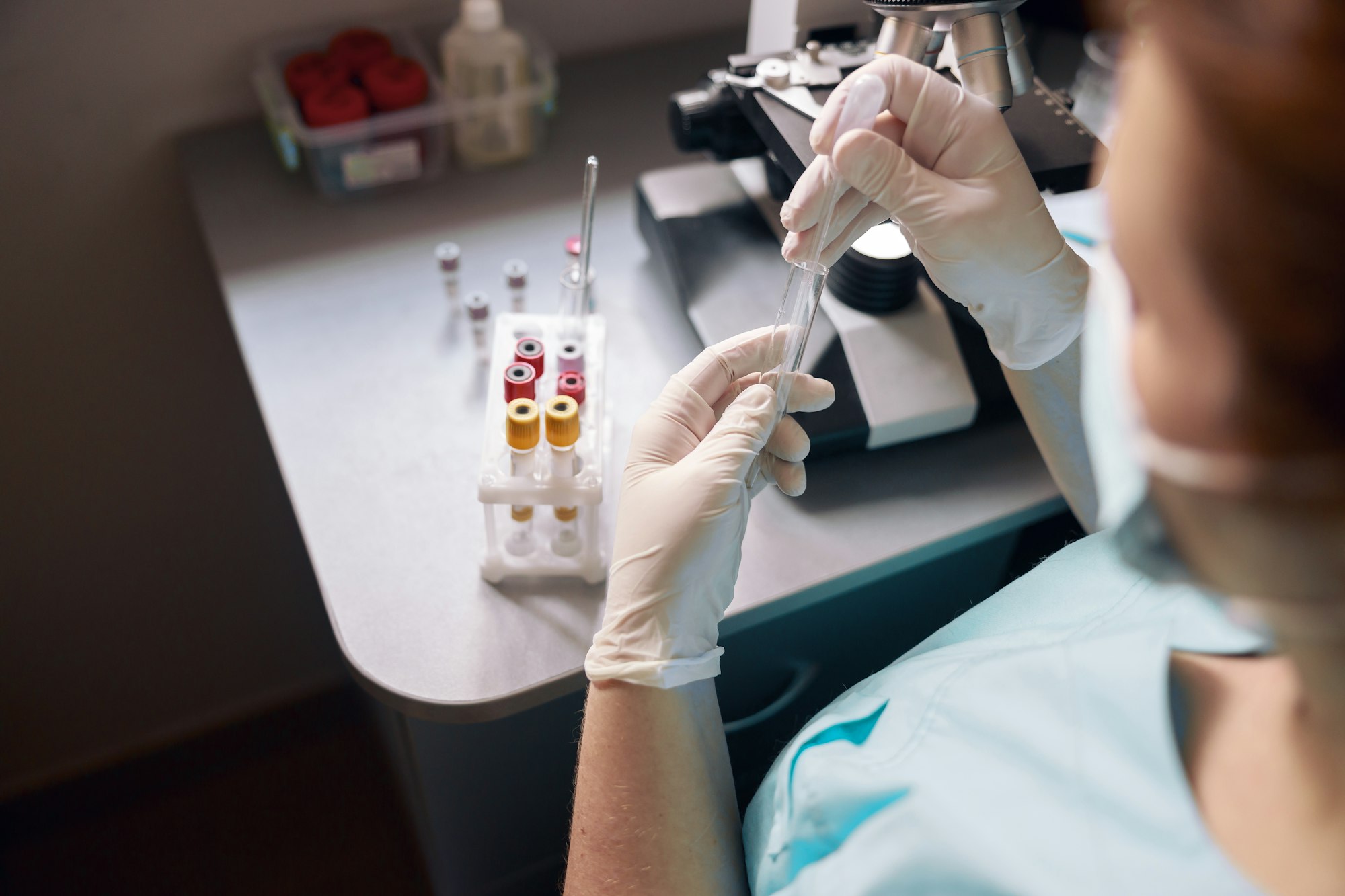 Female lab tech takes sample from test tube to research material at workplace with modern equipment